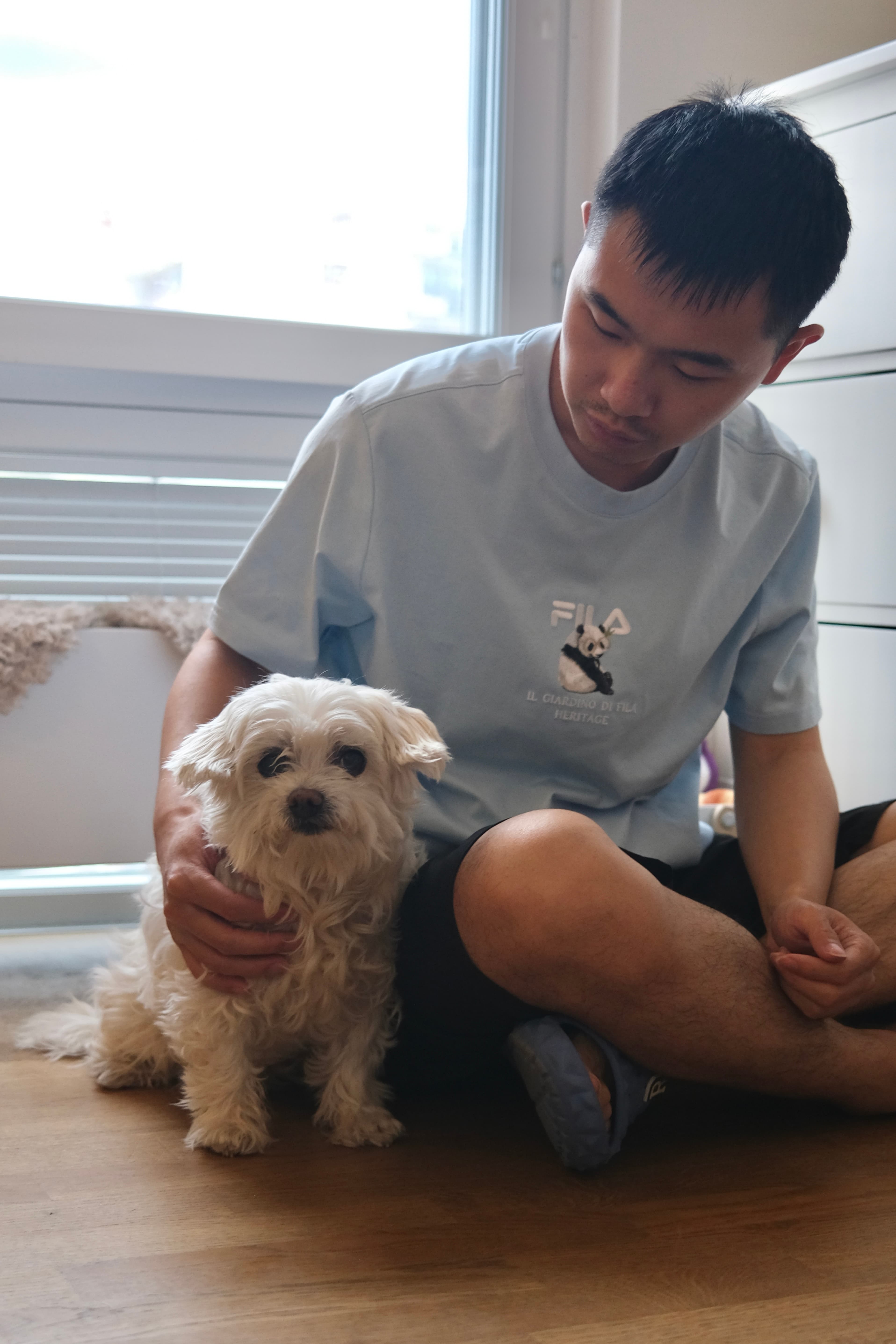 Evan sitting calmly with a small white dog at Mysa Dog Studio