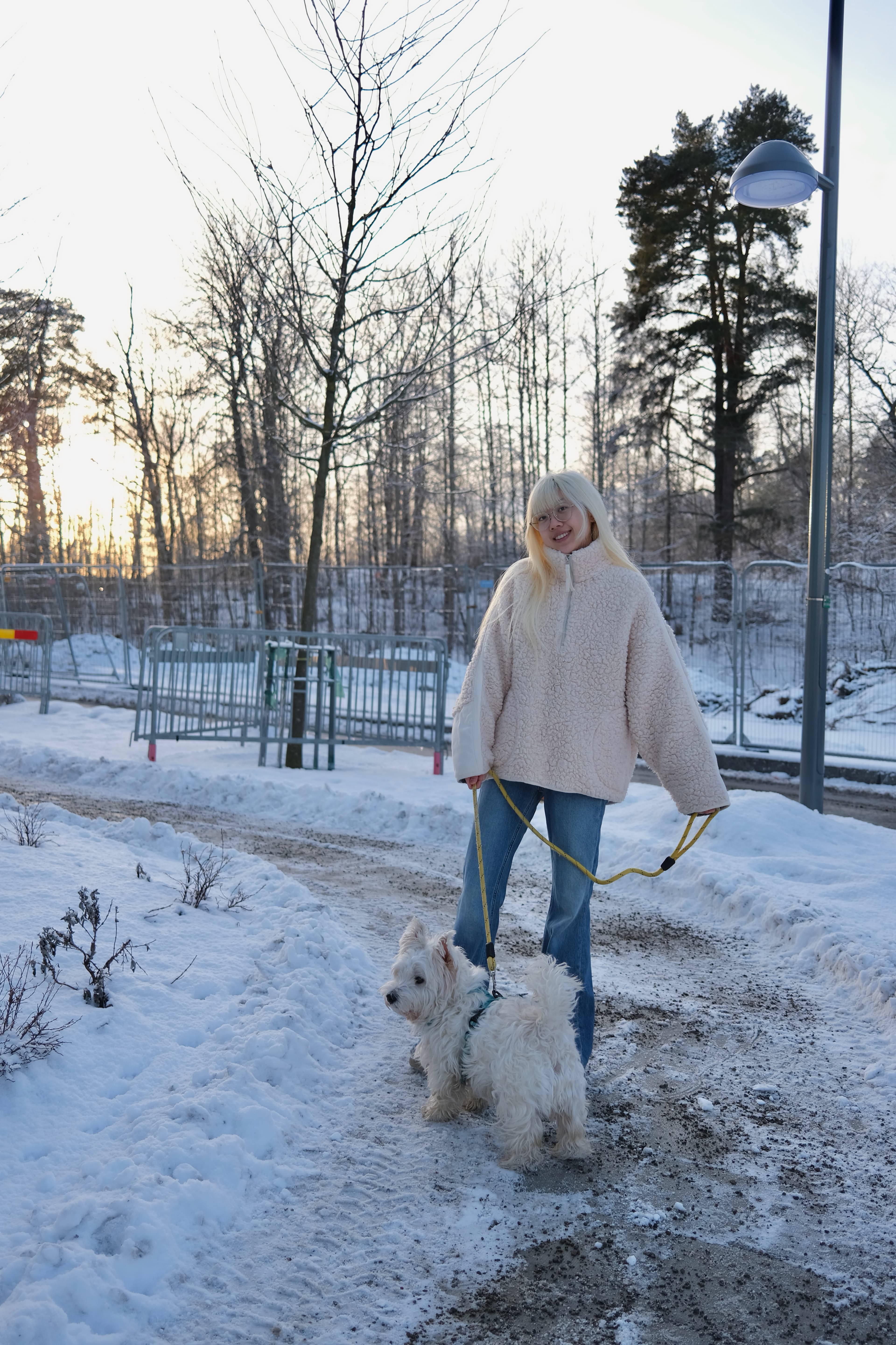Zoe walking a white dog on a snowy path