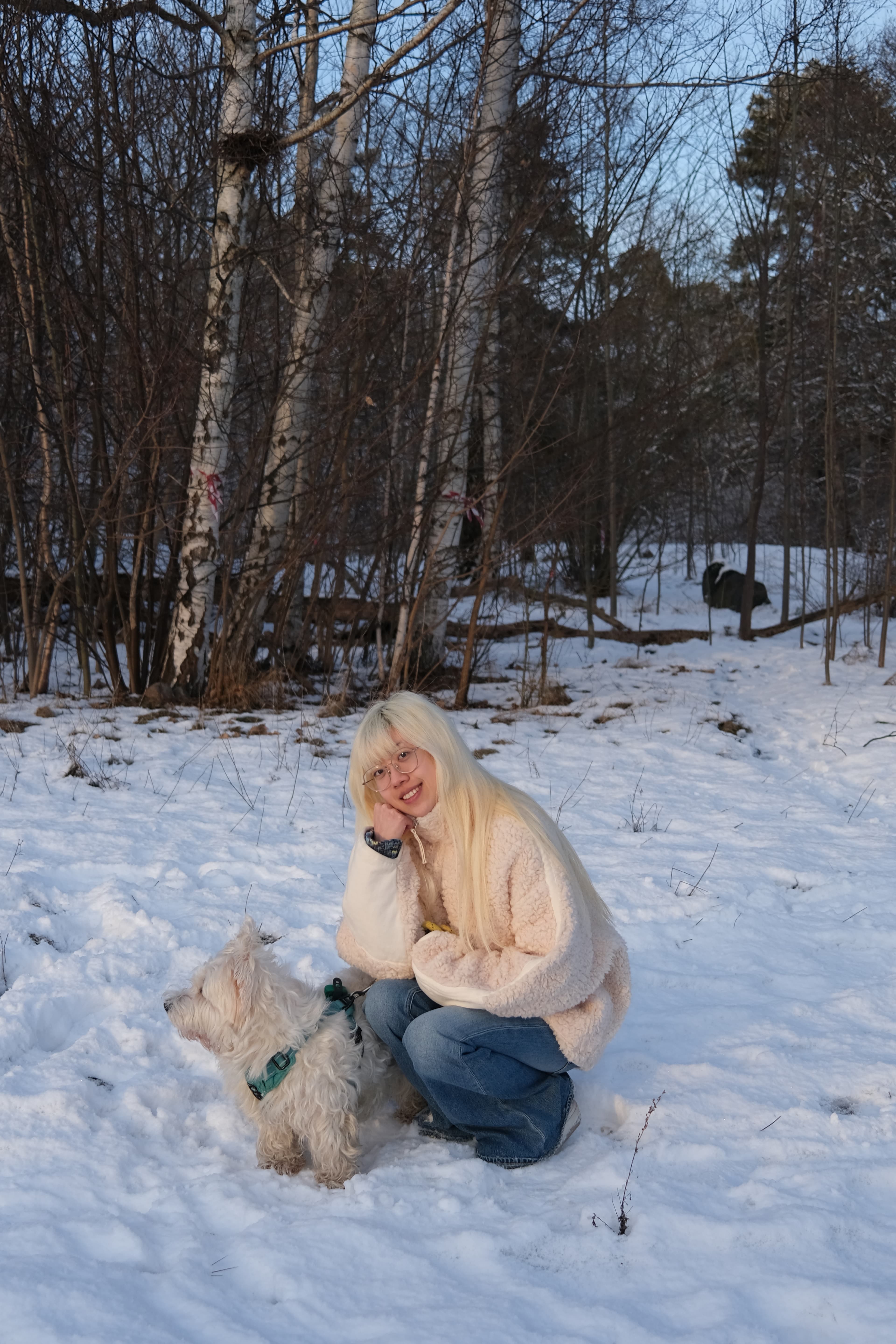 Zoe spending calm time with a white dog in a snowy woodland
